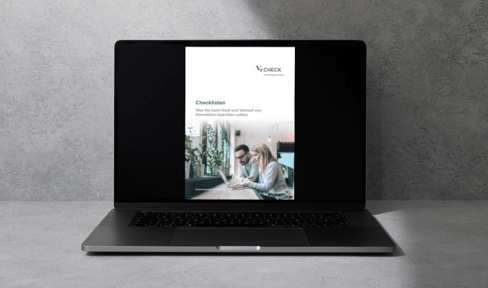 Laptop vor grauem Hintergrund mit geöffnetem eBook "Checklisten Immobilien"